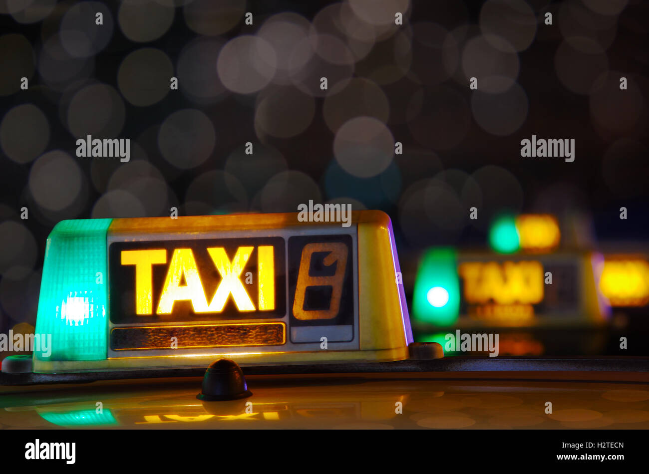 Row of taxi signs from parked taxis in a city street at night Stock Photo