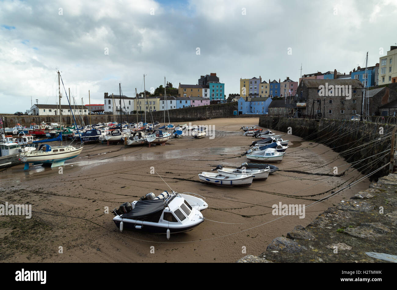 Landscape photo of small fishing boats and dinghies awaiting next incoming tide in Tenby Harbour, Pembrokeshire, Wales Stock Photo