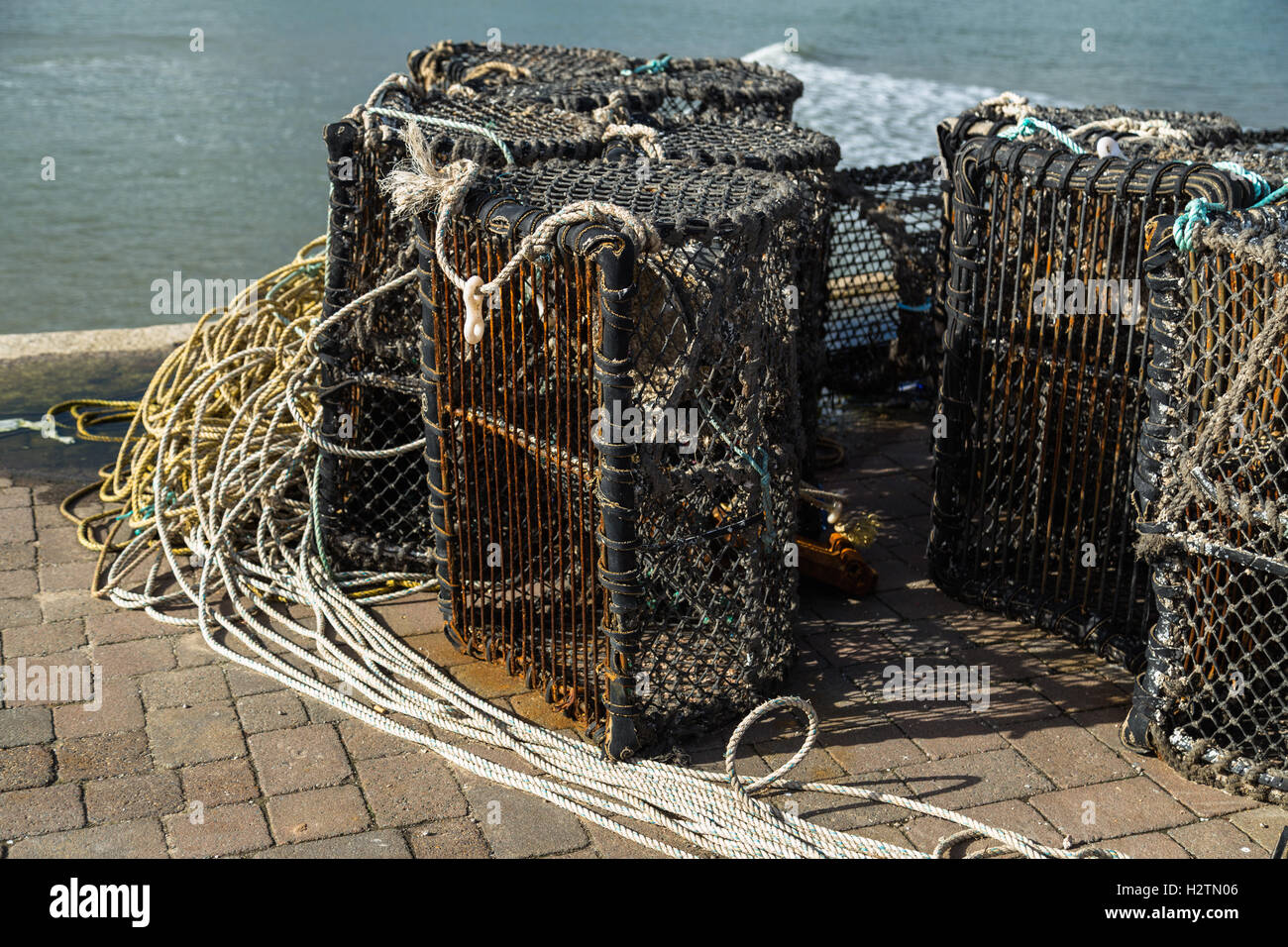 Empty lobster posts lined up on the harbor wall at Tenby in Pembrokeshire Stock Photo