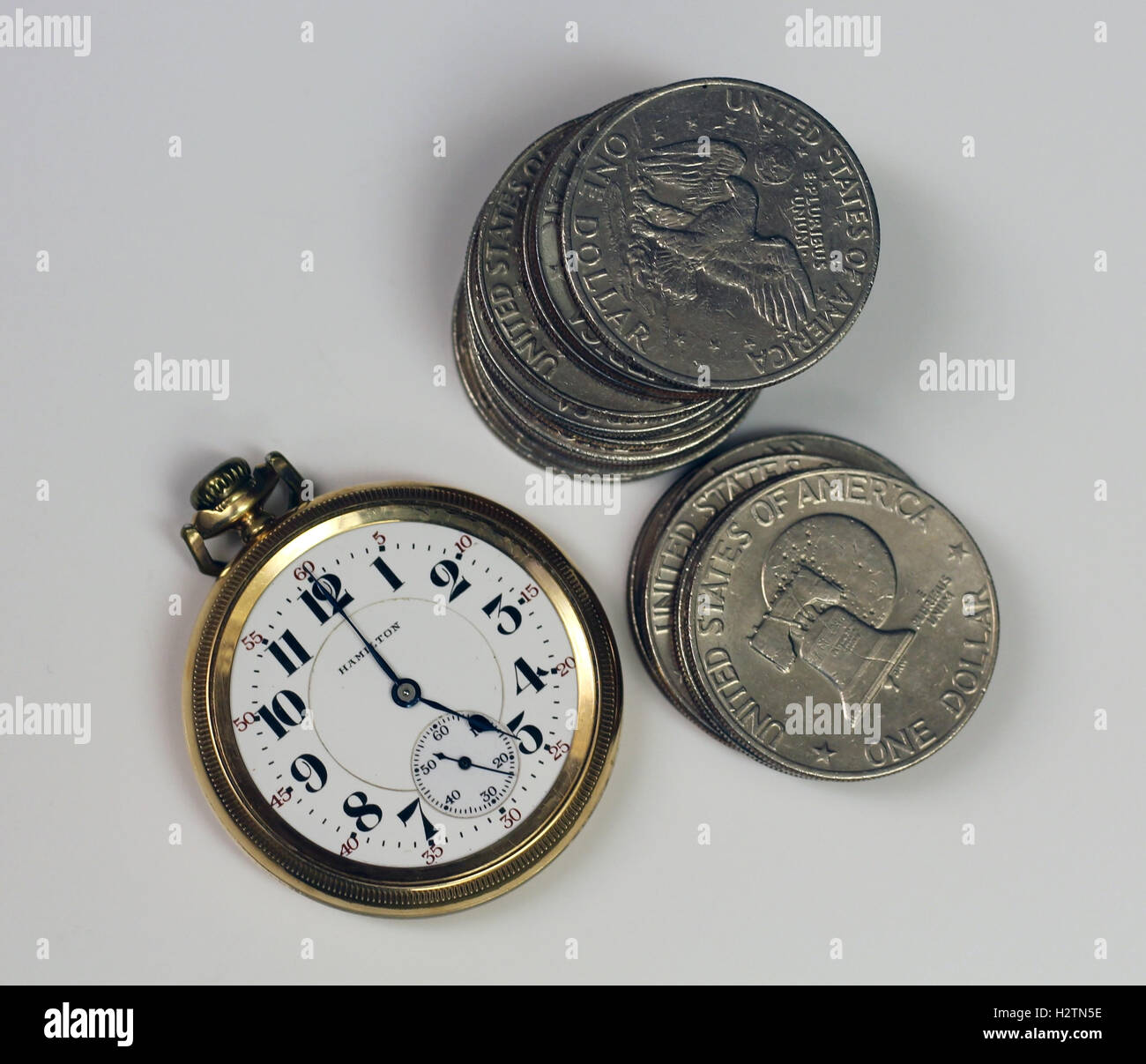 pocket watch with silver dollars around it at 5:00 O'clock, time is money, vintage watch, coins, success, time Stock Photo