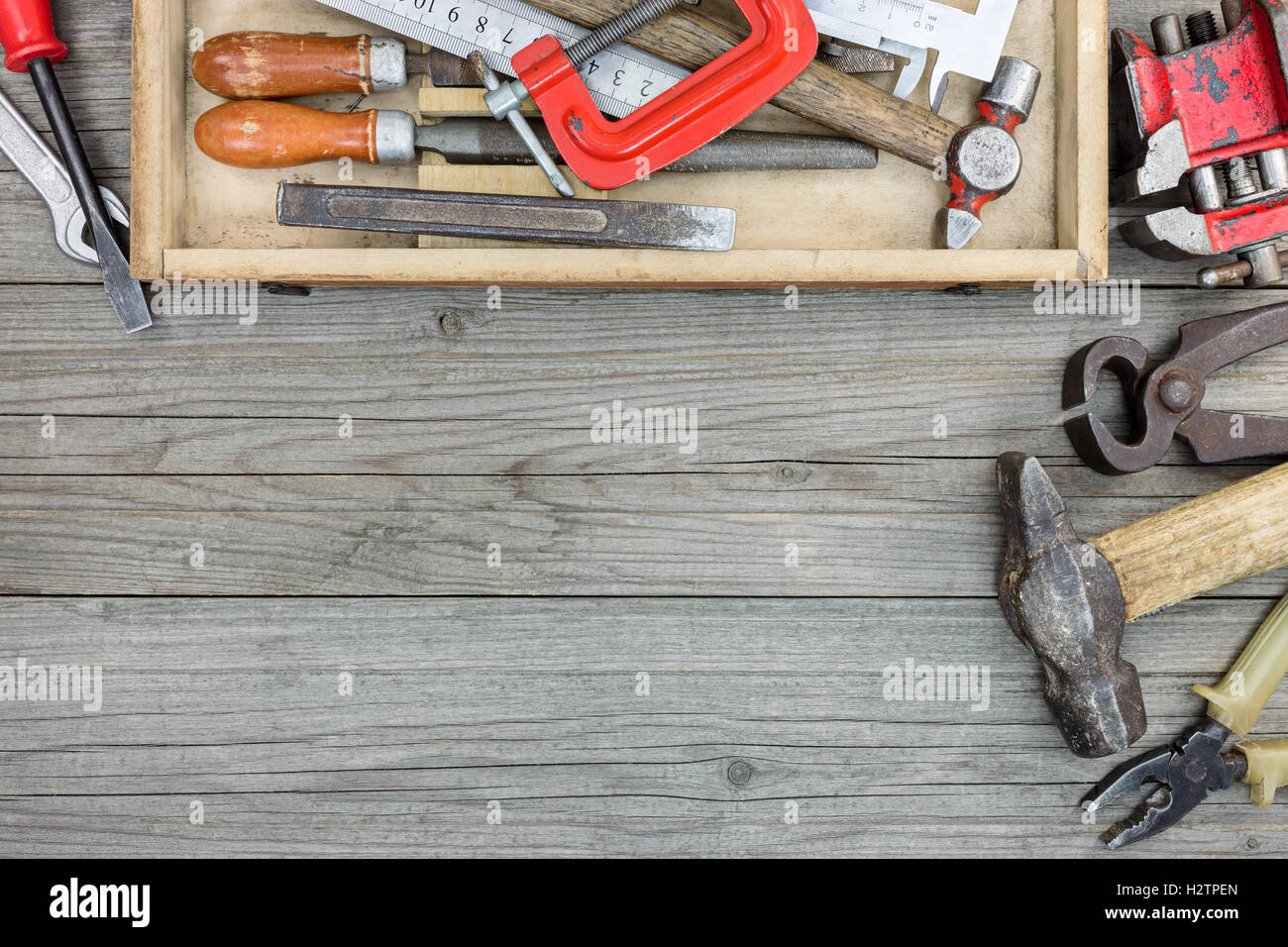 old tool set of rusty hammer, nipper, clamps wrenches and other instruments in toolbox on wooden background Stock Photo