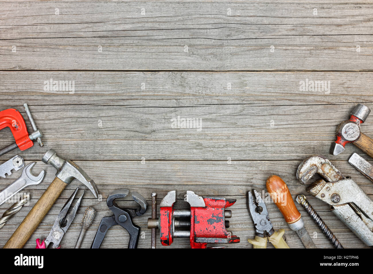 old grungy tool set including hammers, drills, pliers, wrenches and clamps on gray wooden boards background Stock Photo