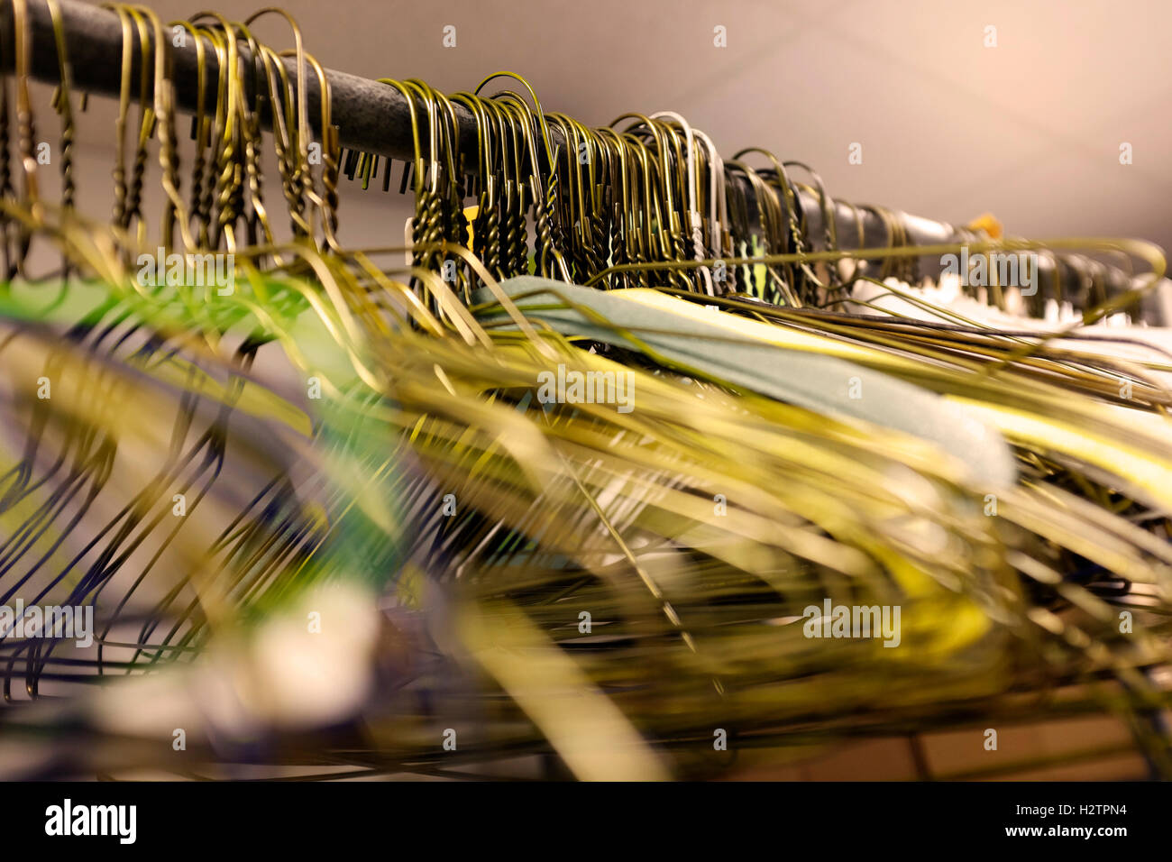 Many several metal wire hangers on pole for hanging clothing in closet