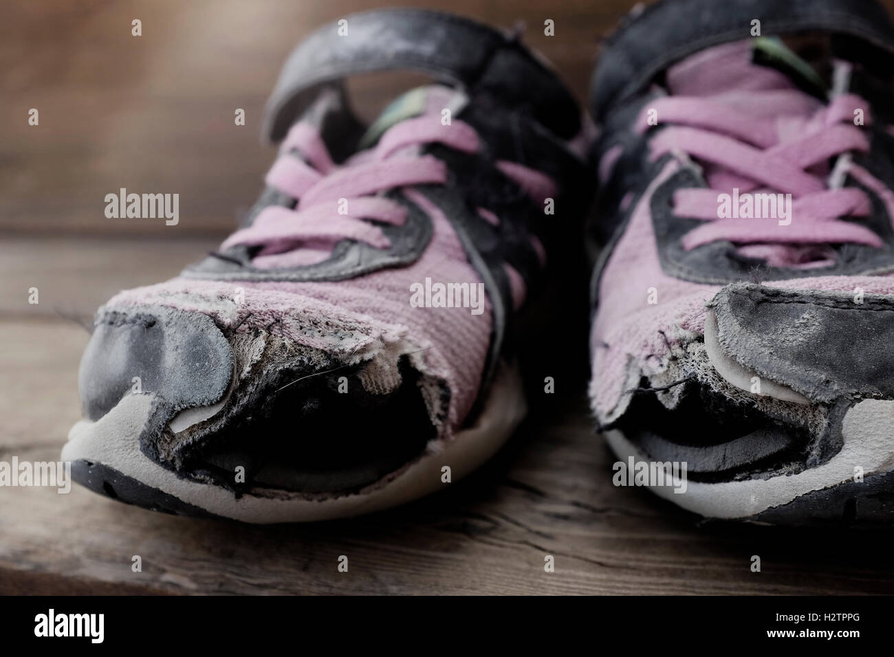 Old shoes with holes worn down shabby for homeless clothing Stock Photo