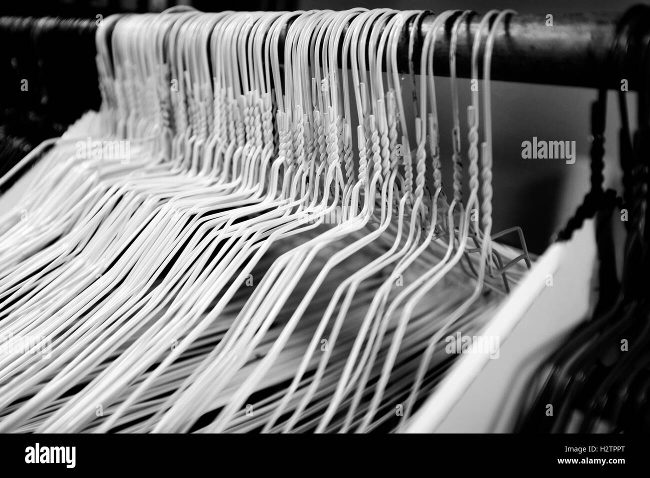 Many several metal wire hangers on pole for hanging clothing in closet storage Stock Photo