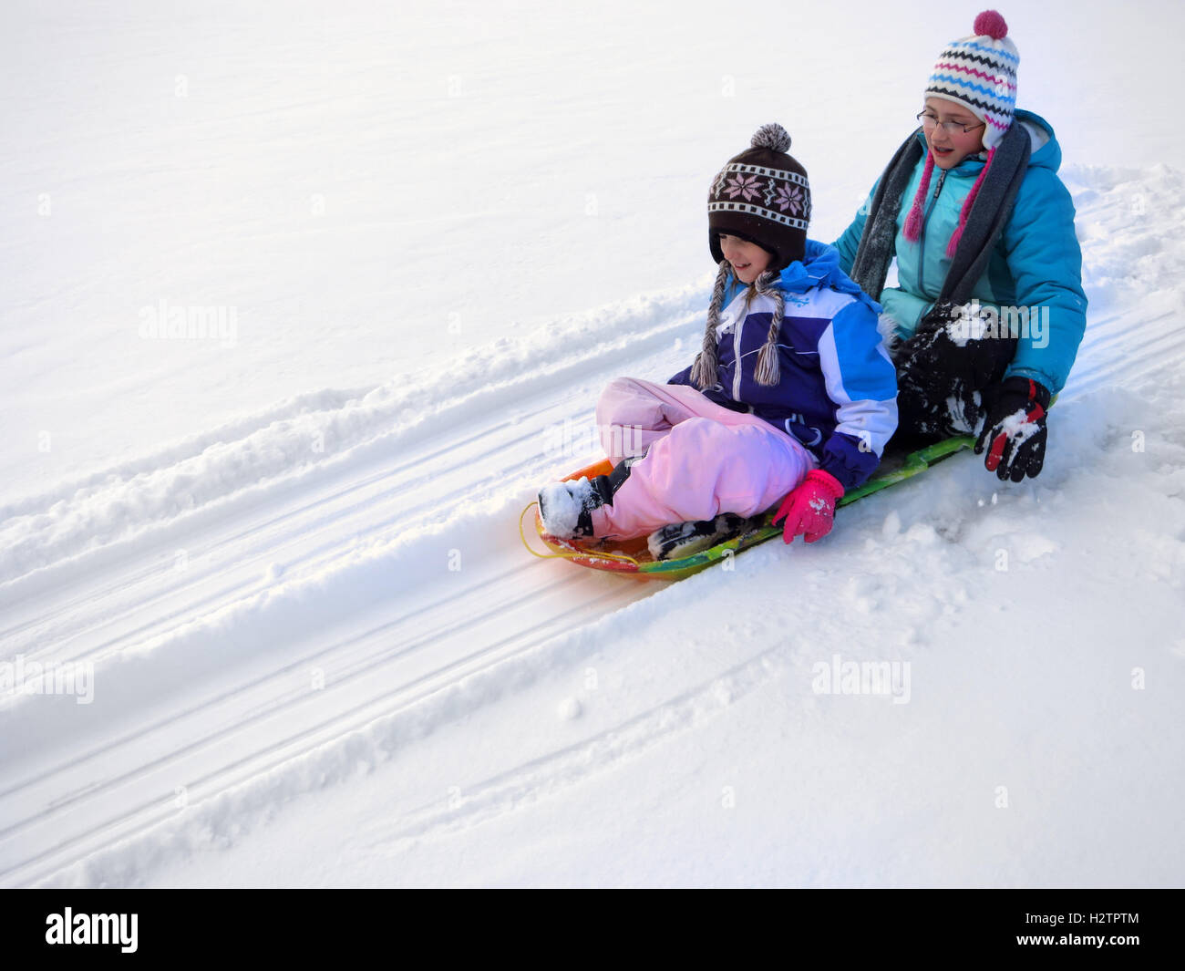 Kids sledding down snowy hill on sled fast speed Stock Photo Alamy