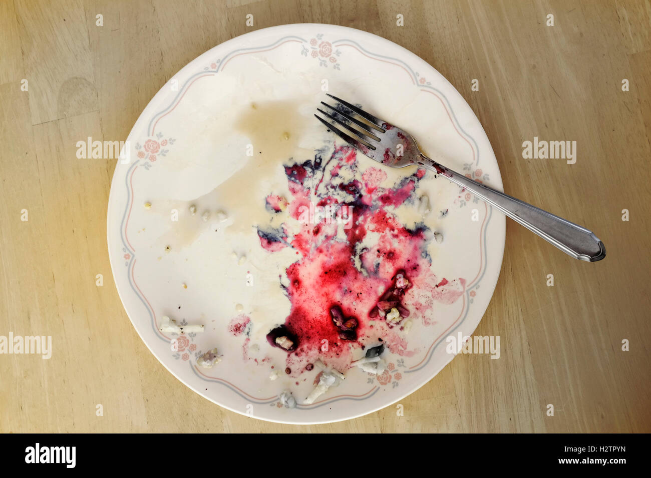 Plate with food berries smeared on surface on table with fork Stock Photo