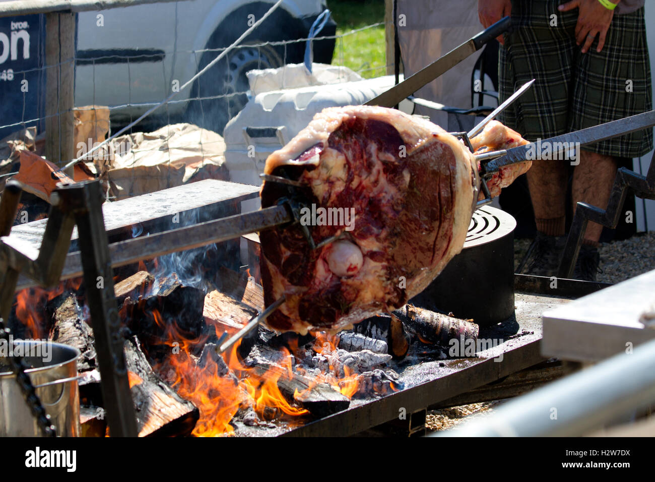 Beef being spit roasted over a wood fire Stock Photo