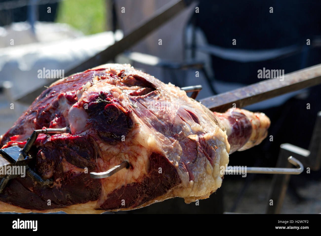 Beef being spit roasted over a wood fire Stock Photo