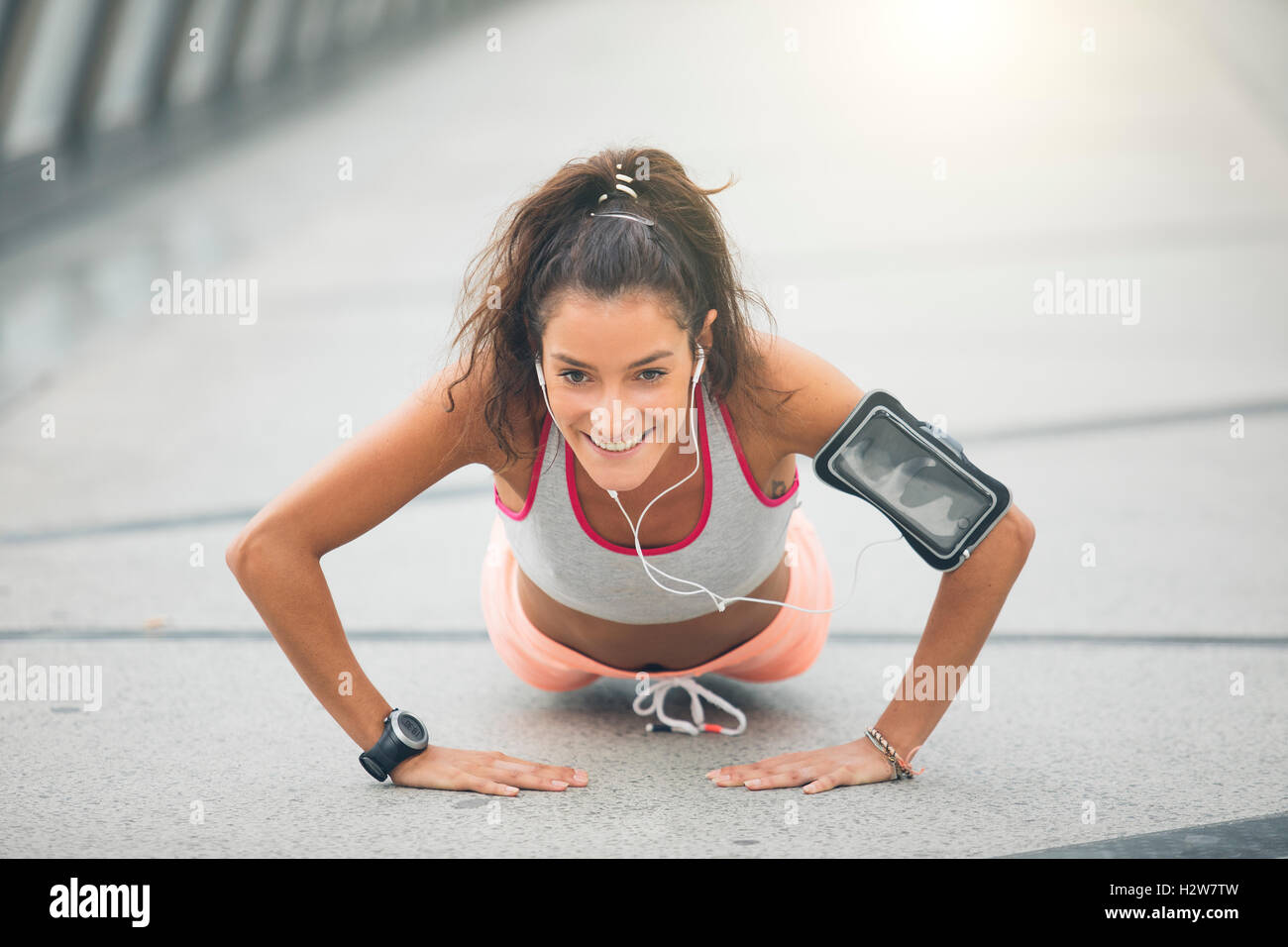 Portrait of a beautiful young woman doing push ups on the street Stock Photo