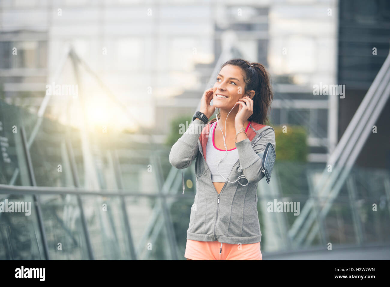 Beautiful young woman runner athlete insert her earphones during training Stock Photo