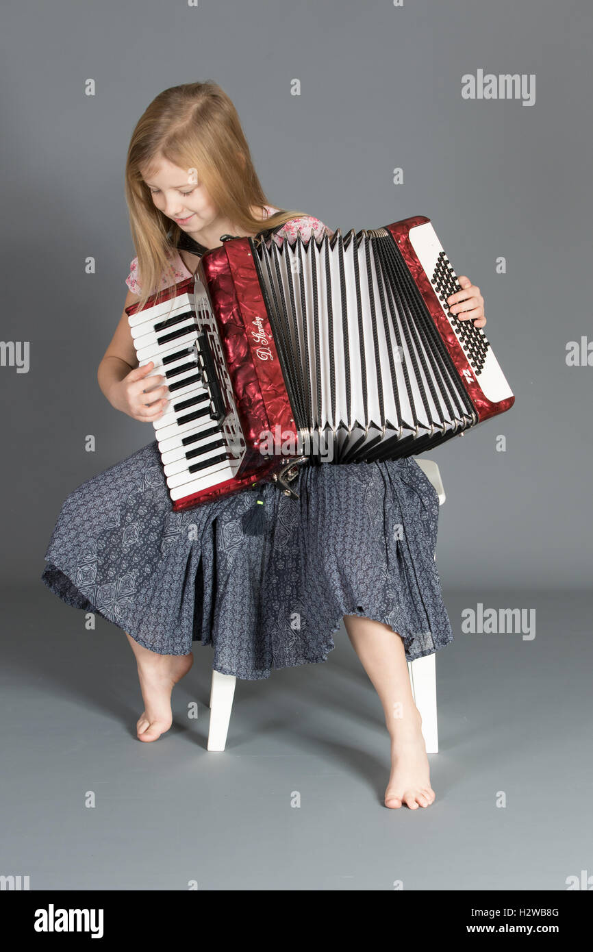 Girl focusing on play key sequence on the accordion. Stock Photo