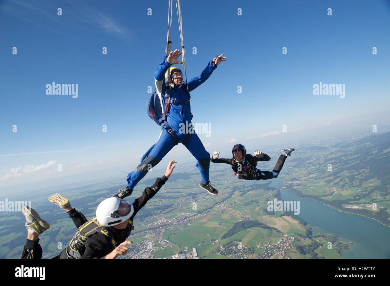 Two instructors assist a student skydiver during the opening of his parachute. Stock Photo