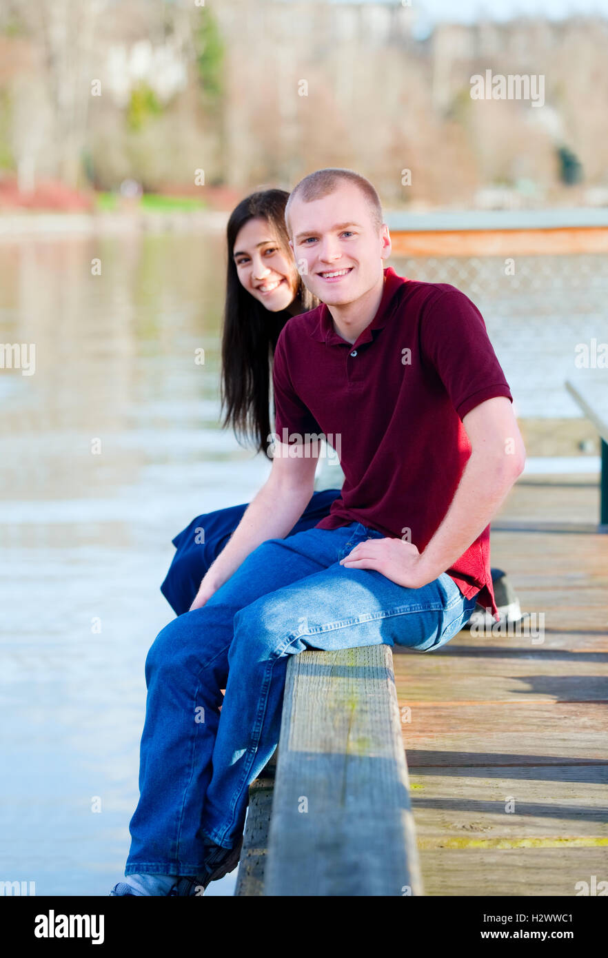 Beautiful interracial couple sitting on wooden dock over lake Stock Photo