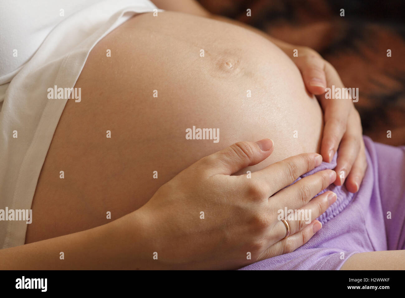 Young pregnant woman holding and touching her belly, closeup Stock Photo