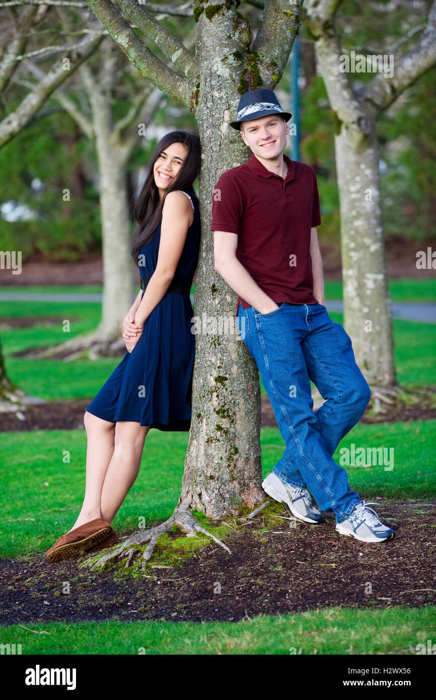 Young interracial couple standing by tree Stock Photo