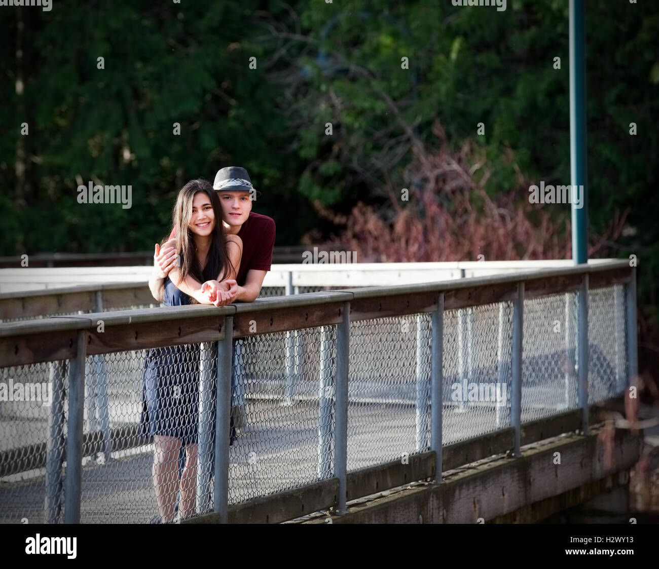 Young interracial couple standing on bridge over water Stock Photo