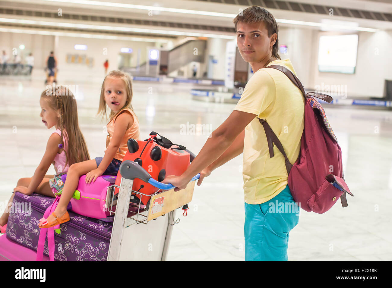 Young father and little cute daughters with luggage in airport Stock Photo
