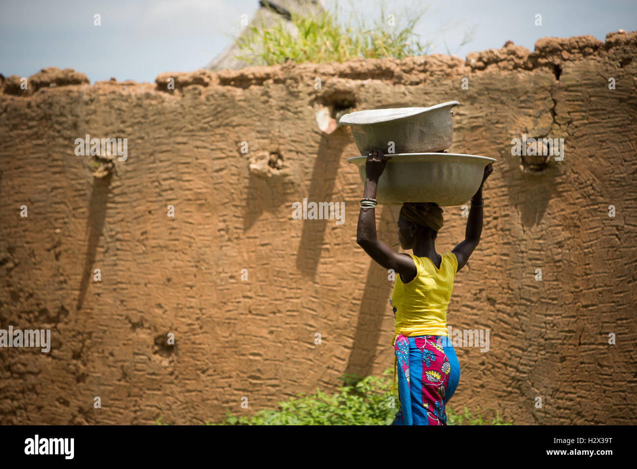 A woman carries basins on her head in rural Réo department, Burkina Faso, West Africa. Stock Photo