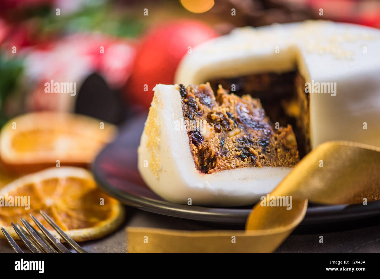 Slicing Christmas traditional festive fruit cake, Christmas ornaments and decorations Stock Photo