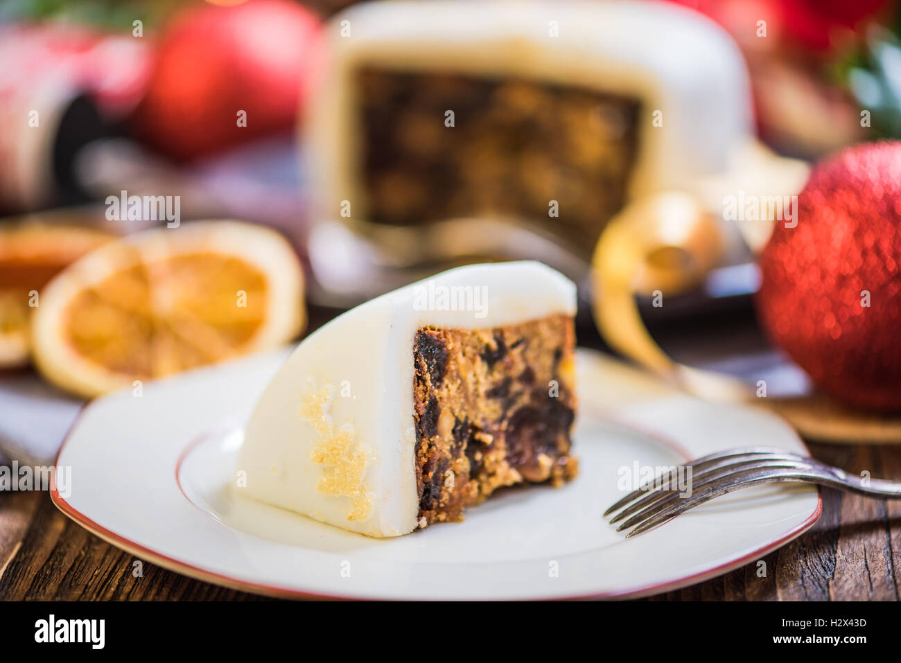 Slicing Christmas traditional festive fruit cake, Christmas ornaments and decorations Stock Photo