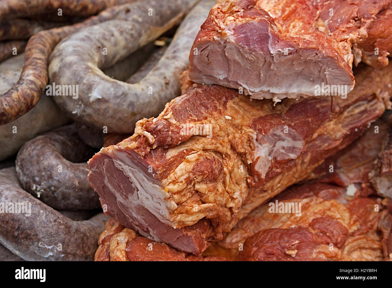 Various smoked meat specialties, placed on a table and exposed on sale. Stock Photo
