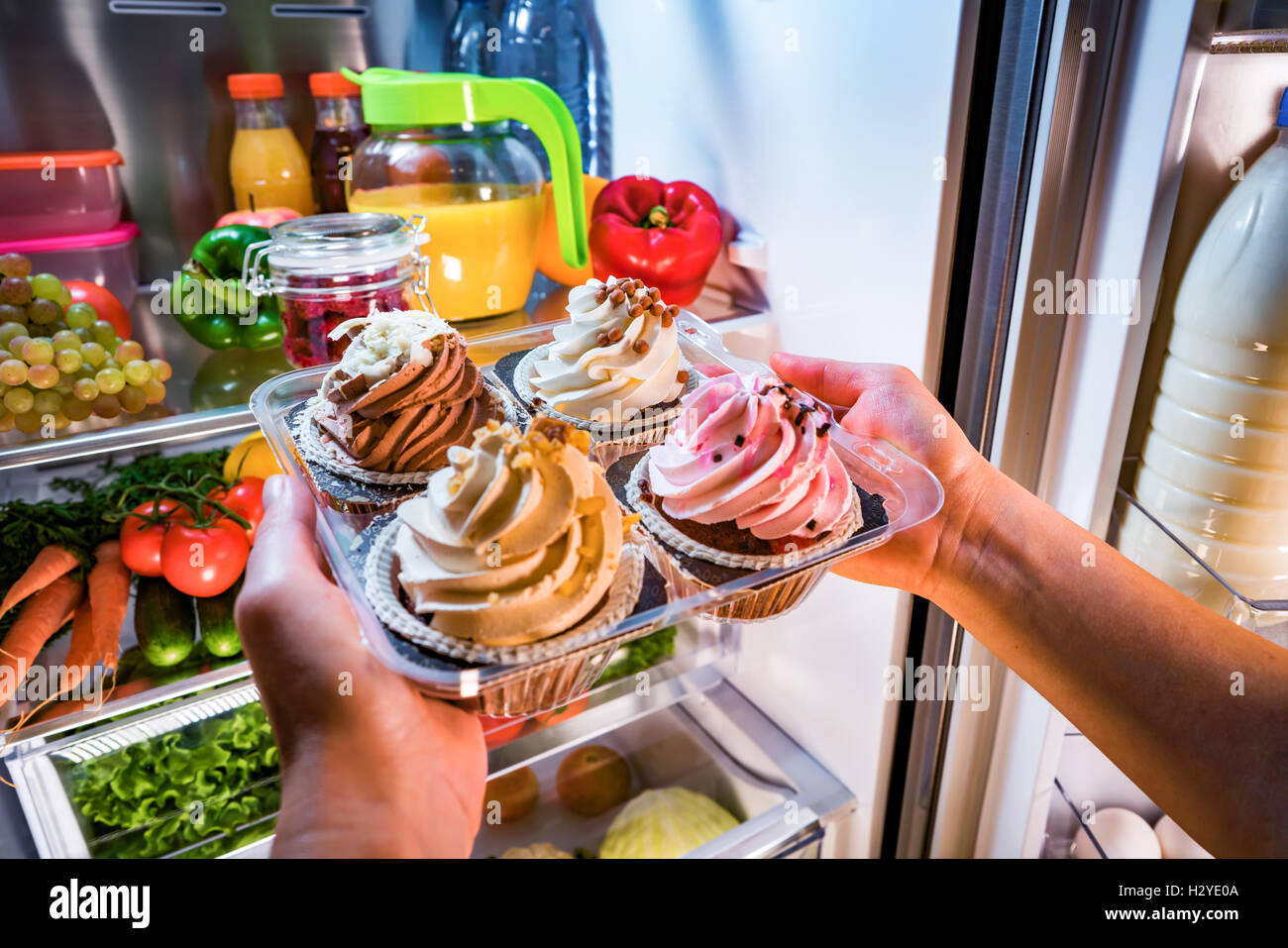 Woman takes the sweet cake from the open refrigerator Stock Photo