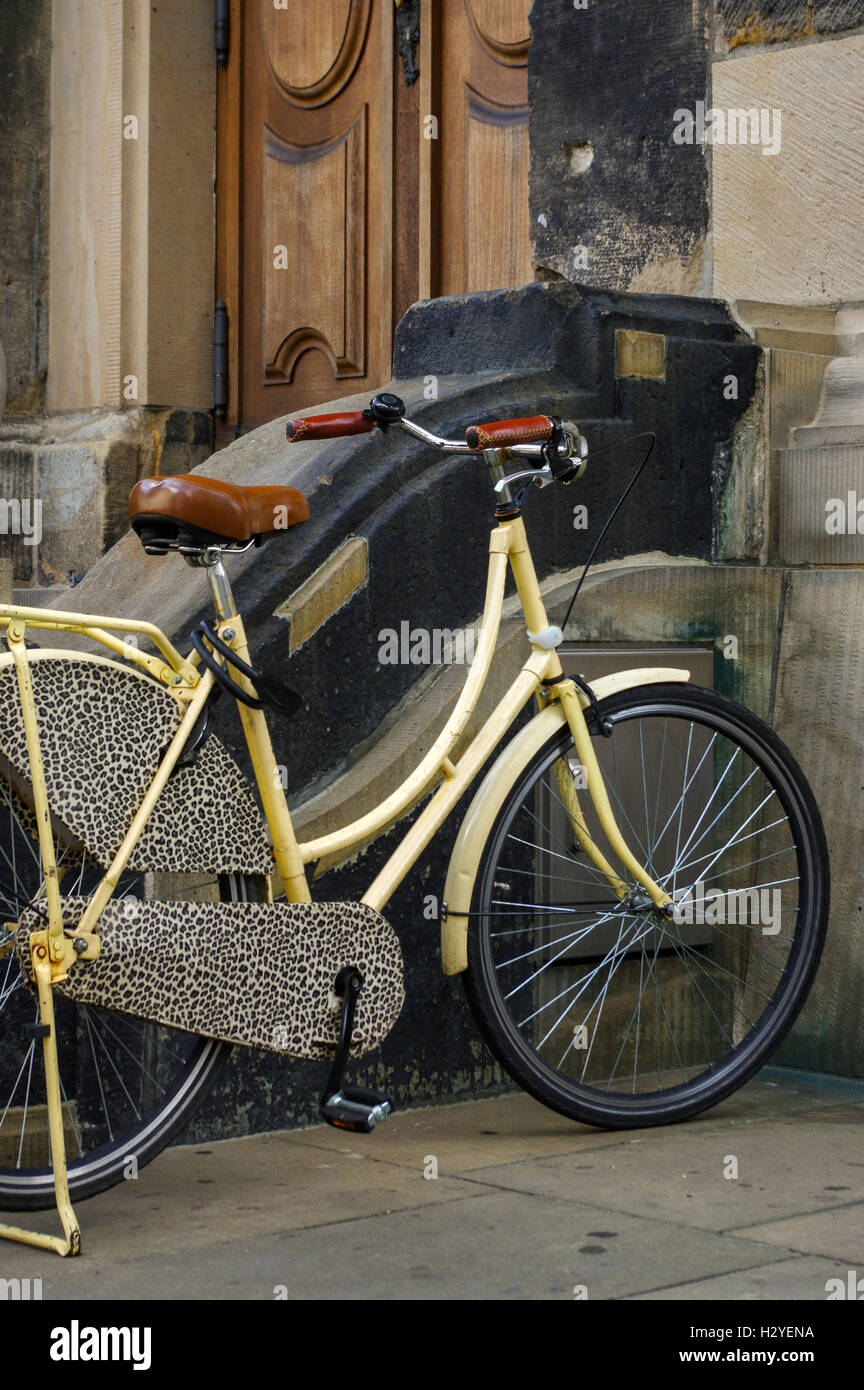 an old yellow bicycle. leather seat with shock absorbers and wheel in front of a church Stock Photo Alamy