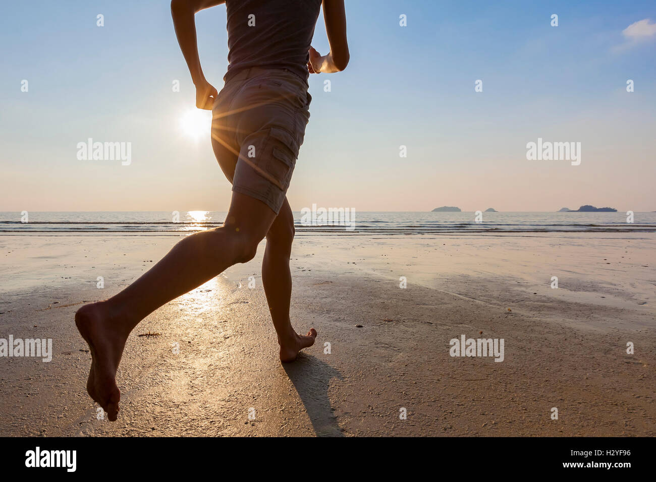 Young active woman running on the beach at sunset for healthy lifestyle and wellness Stock Photo