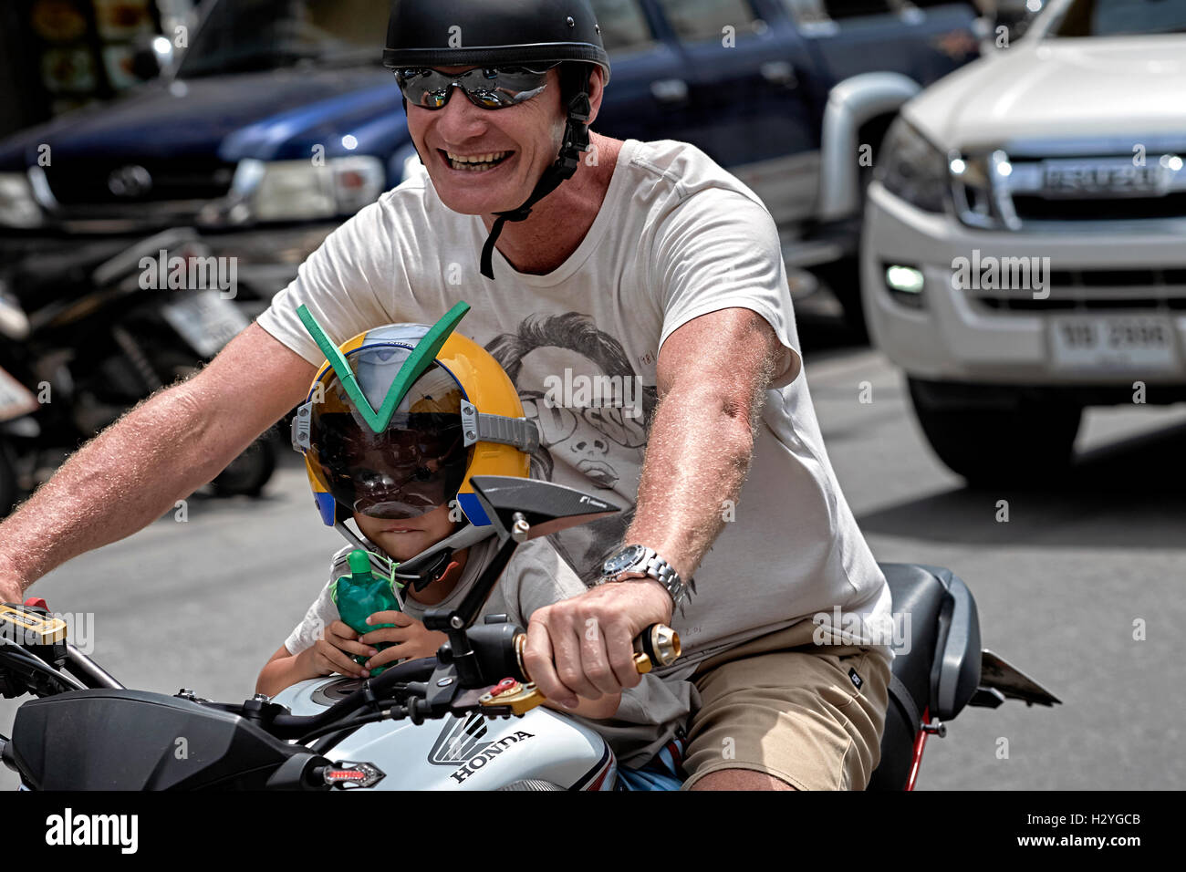 Child motorcycle. Father carrying his young child on a motorbike through traffic. Stock Photo