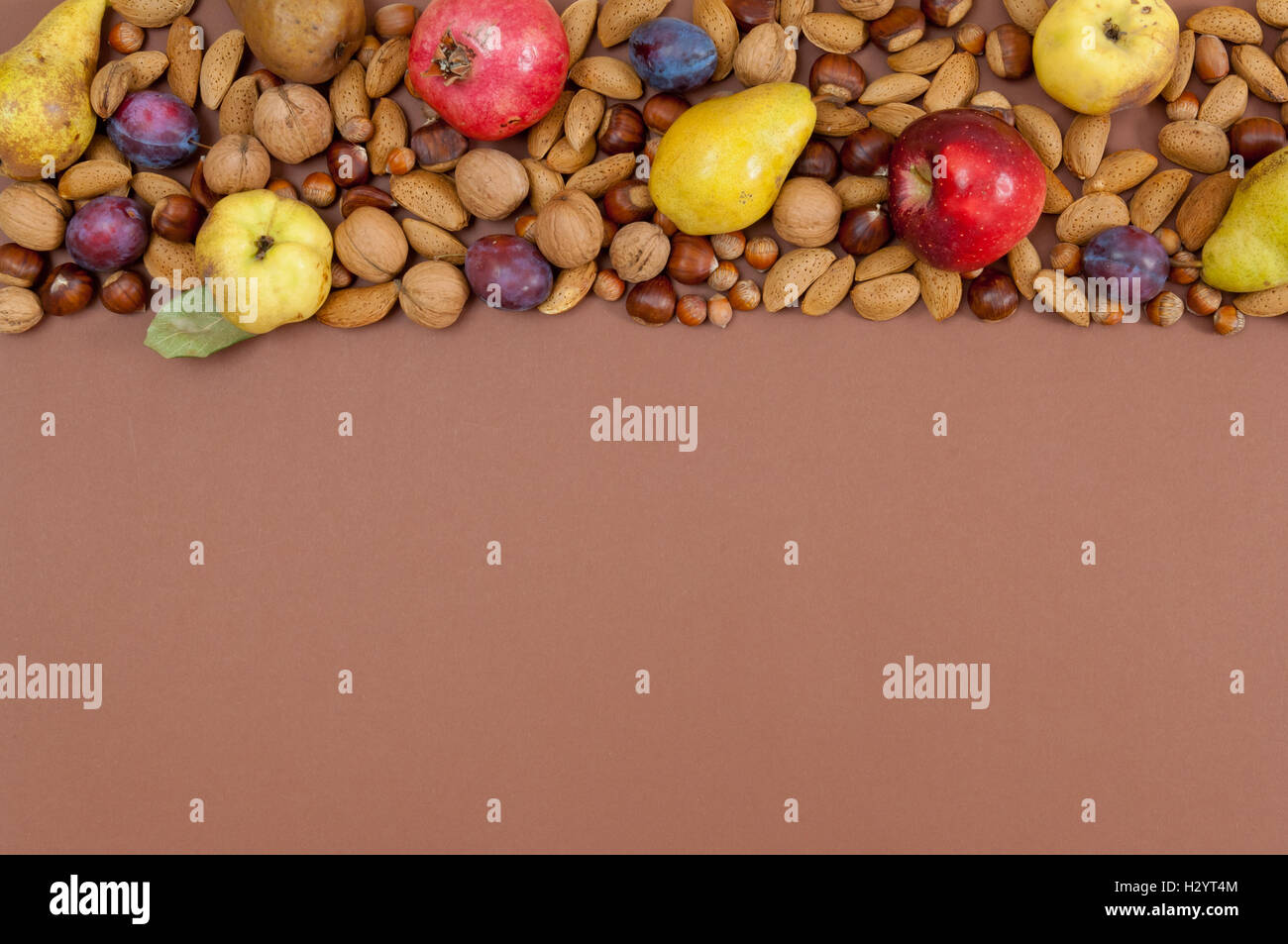 Autumn fruits and nuts on brown background Stock Photo