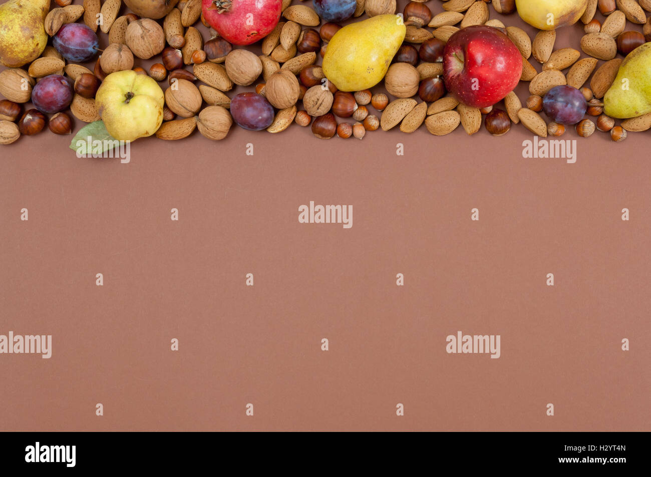 Autumn fruits and nuts on brown background Stock Photo