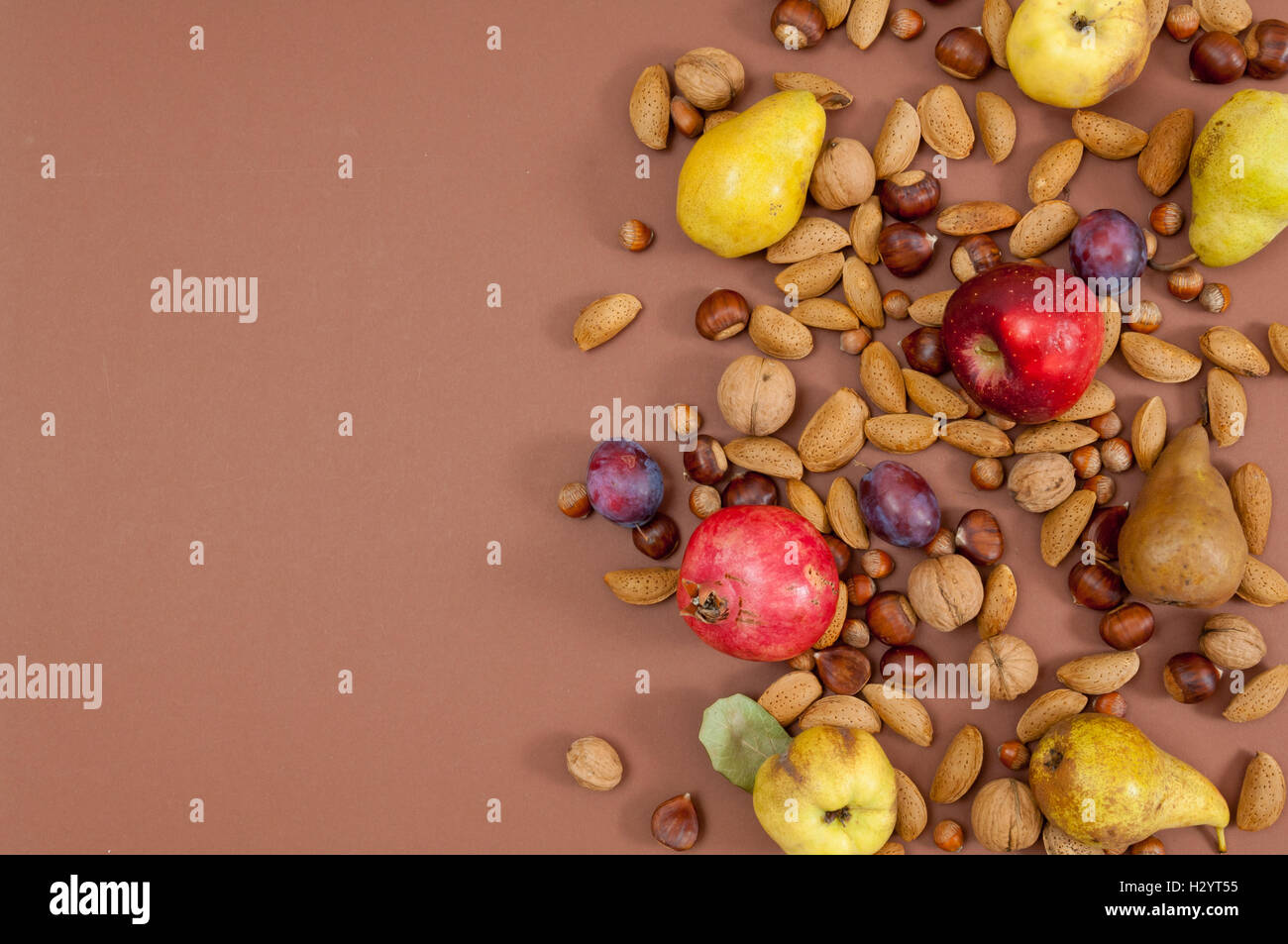 Autumn fruits and nuts on brown background Stock Photo