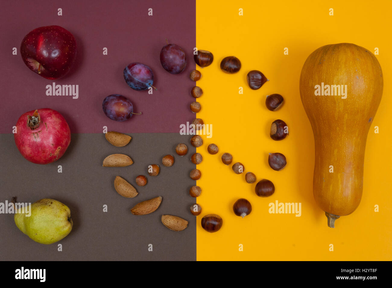 Autumn fruits forming peace sign on orange and brown split background Stock Photo