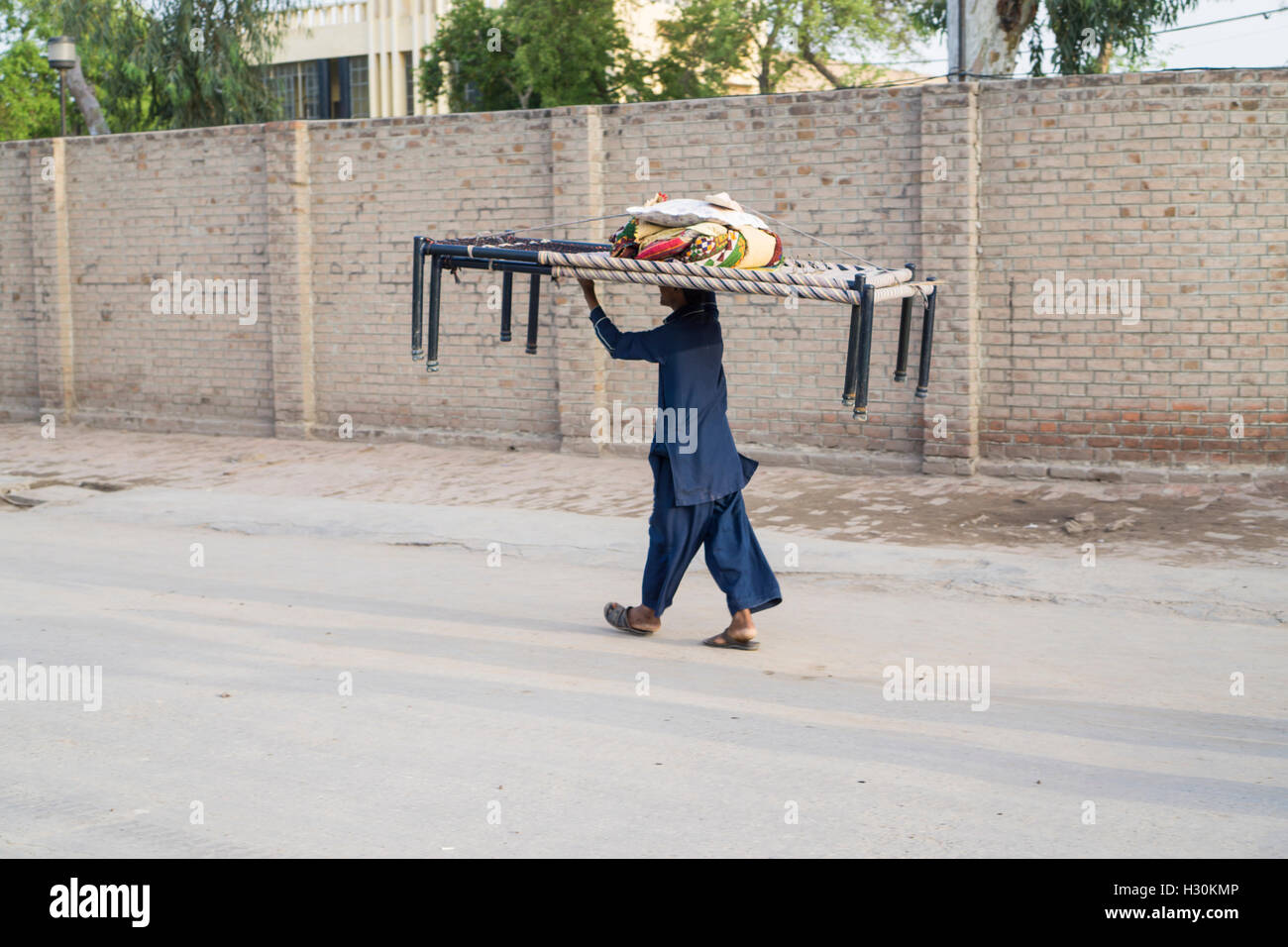 Man carrying two beds on his head Stock Photo