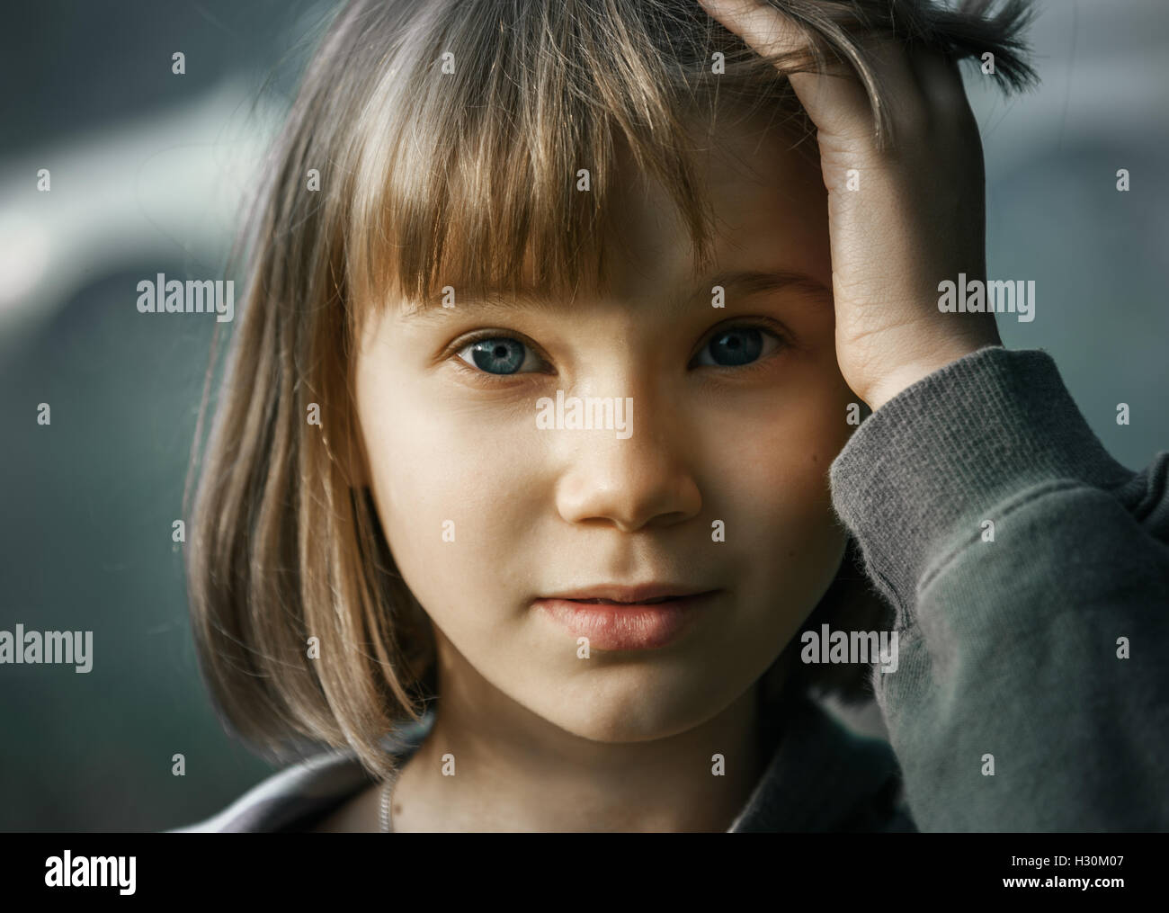 Sad Teenager Girl With Short Blonde Hair And Blue Eyes On A Gray