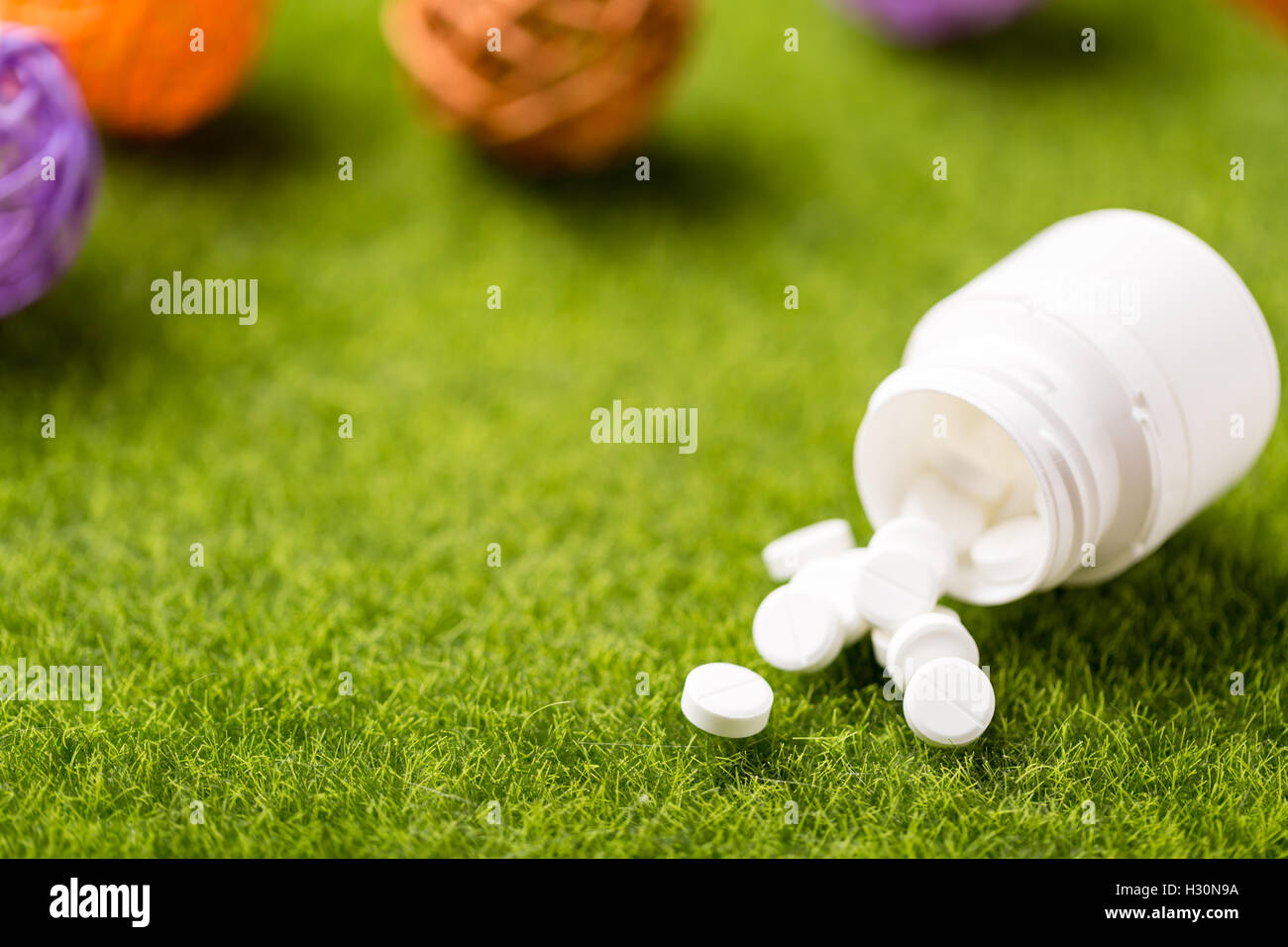 Heap of white round pills on green grass background Stock Photo