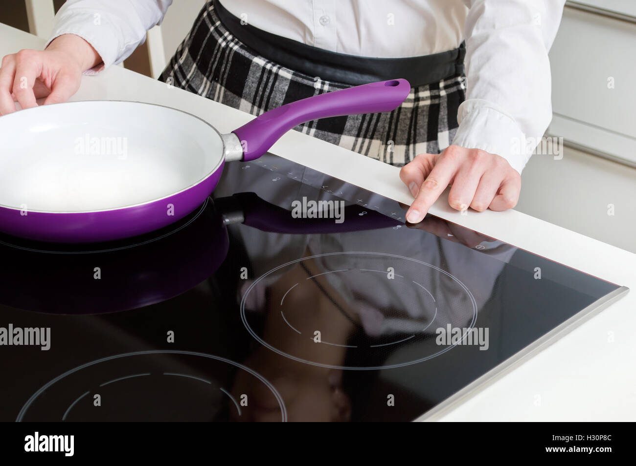 A woman is turning on induction hob. Stock Photo