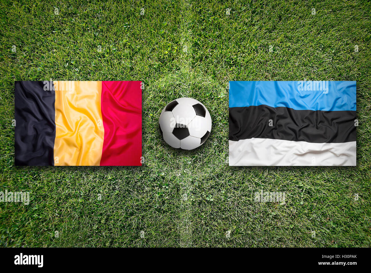 Belgium vs. Estonia flags on green soccer field Stock Photo