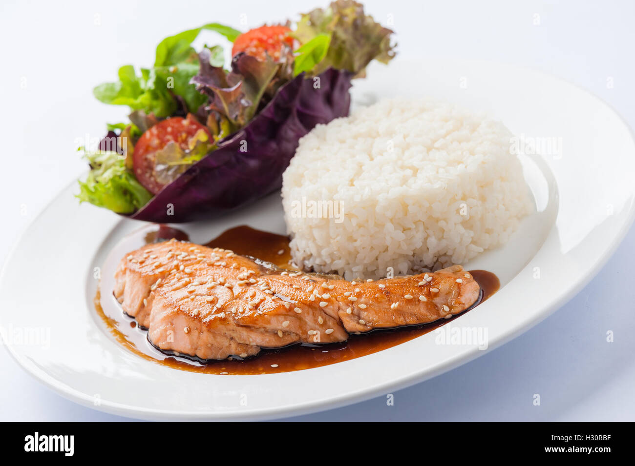 Fusion food style grilled salmon dressed with Japanese sweet sauce (Teriyaki) including Thai rice garnished with vegetables in c Stock Photo