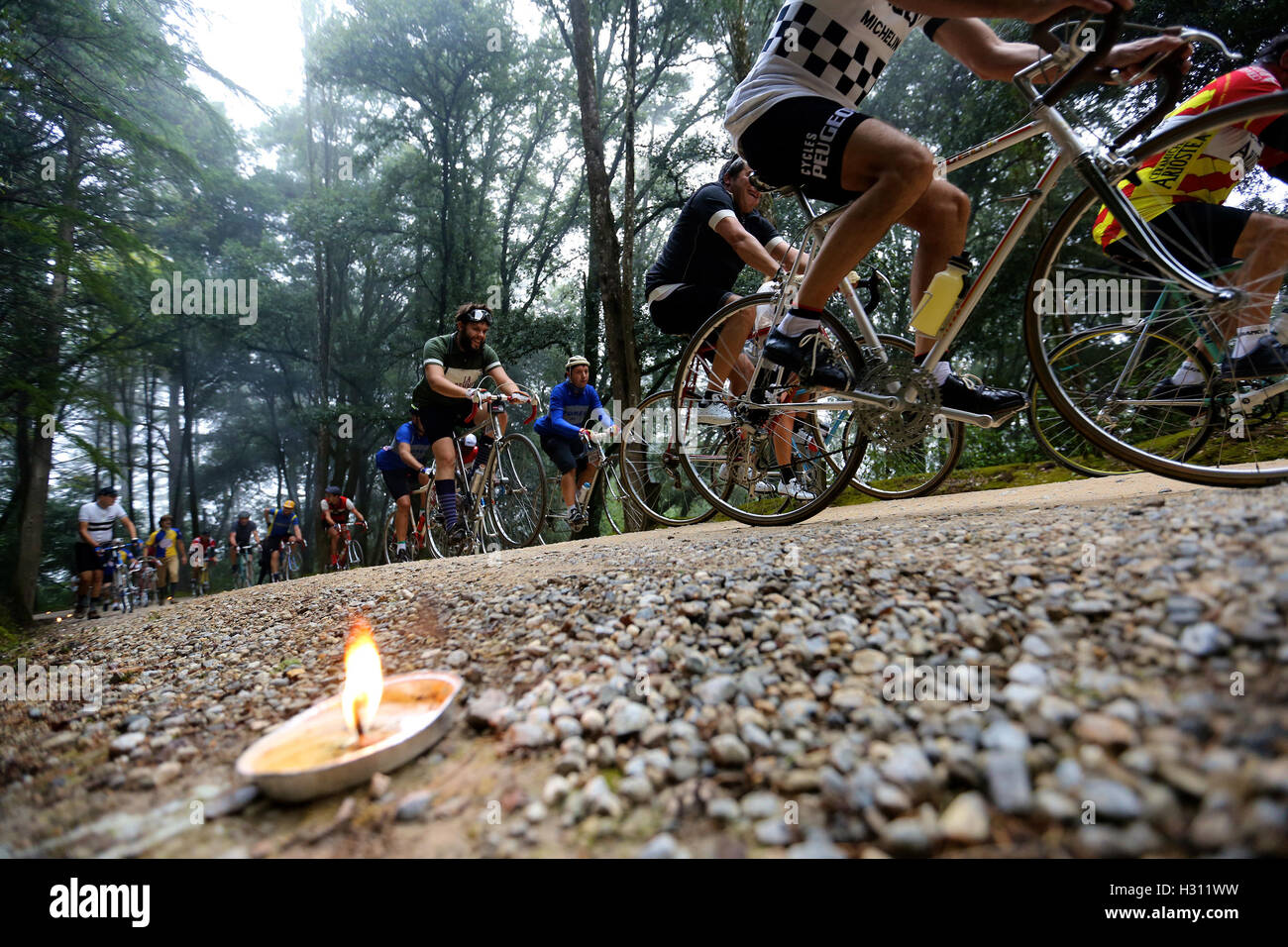 Tuscany, Italy. 2nd Oct, 2016. Cyclists ride past a forest where candles are lit to lighten the gravel road during the "Eroica" cycling event for old bikes in the Chianti area of Tuscany, Italy, on Oct. 2, 2016. More than 6,000 cyclists from 65 countries and regions, wearing vintage cycling jerseys, riding vintage bicycles built in 1987 or earlier, took part in the "Eroica" (heroic) cycling event through the Strade Bianche, the gravel roads of the Chianti area of Tuscany. © Jin Yu/Xinhua/Alamy Live News Stock Photo