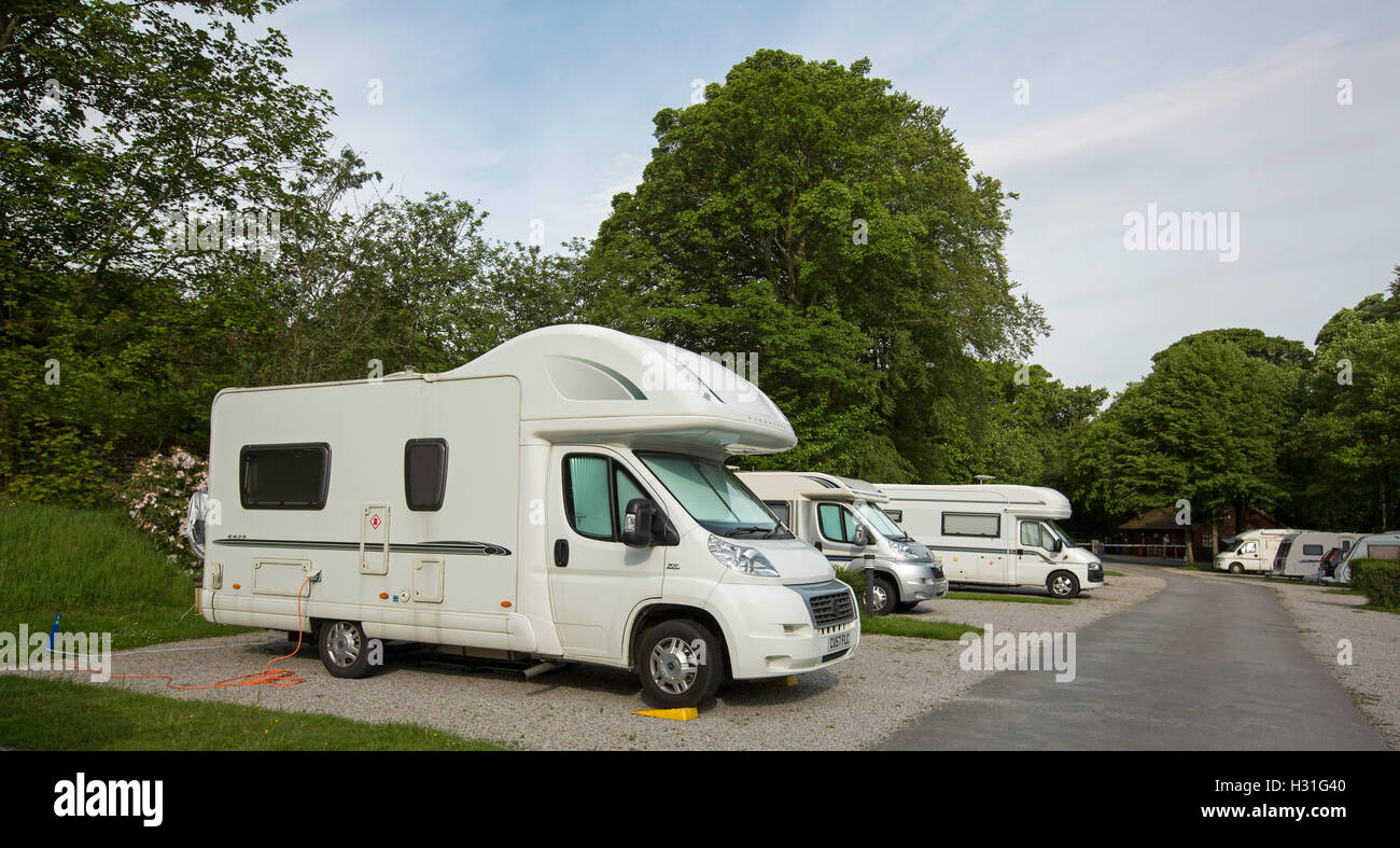 Group of motorhomes / campervans parked among landscape dominated by