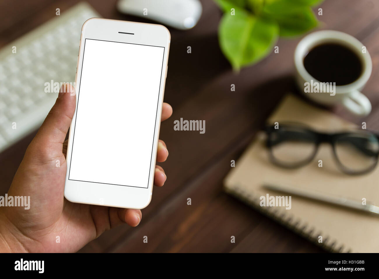close up hand holding phone over work table, mockup phone blank screen for app screen adjustment Stock Photo