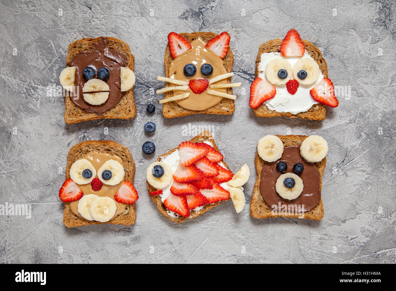 Funny animal faces toasts with spreads, banana, strawberry and blueberry Stock Photo