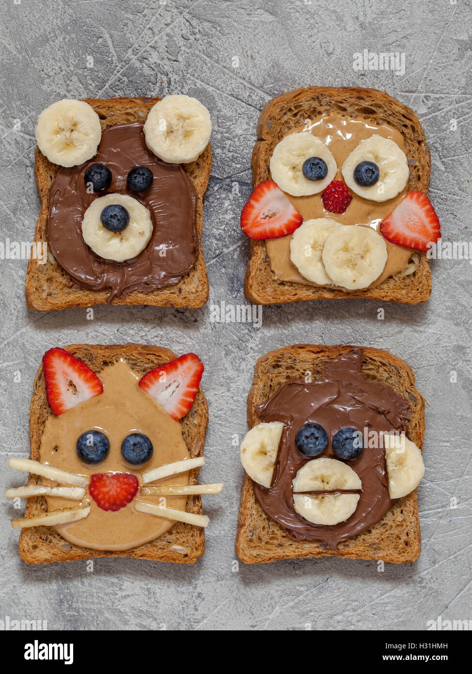Funny animal faces toasts with spreads, banana, strawberry and blueberry Stock Photo
