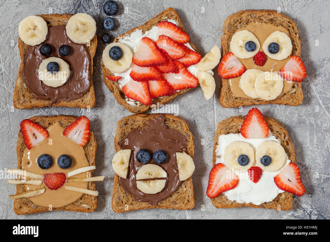 Funny animal faces toasts with spreads, banana, strawberry and blueberry Stock Photo