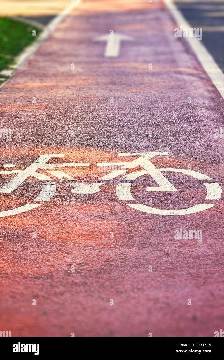 Red bike lane on sidewalk with painted white bicycle and arrow signs