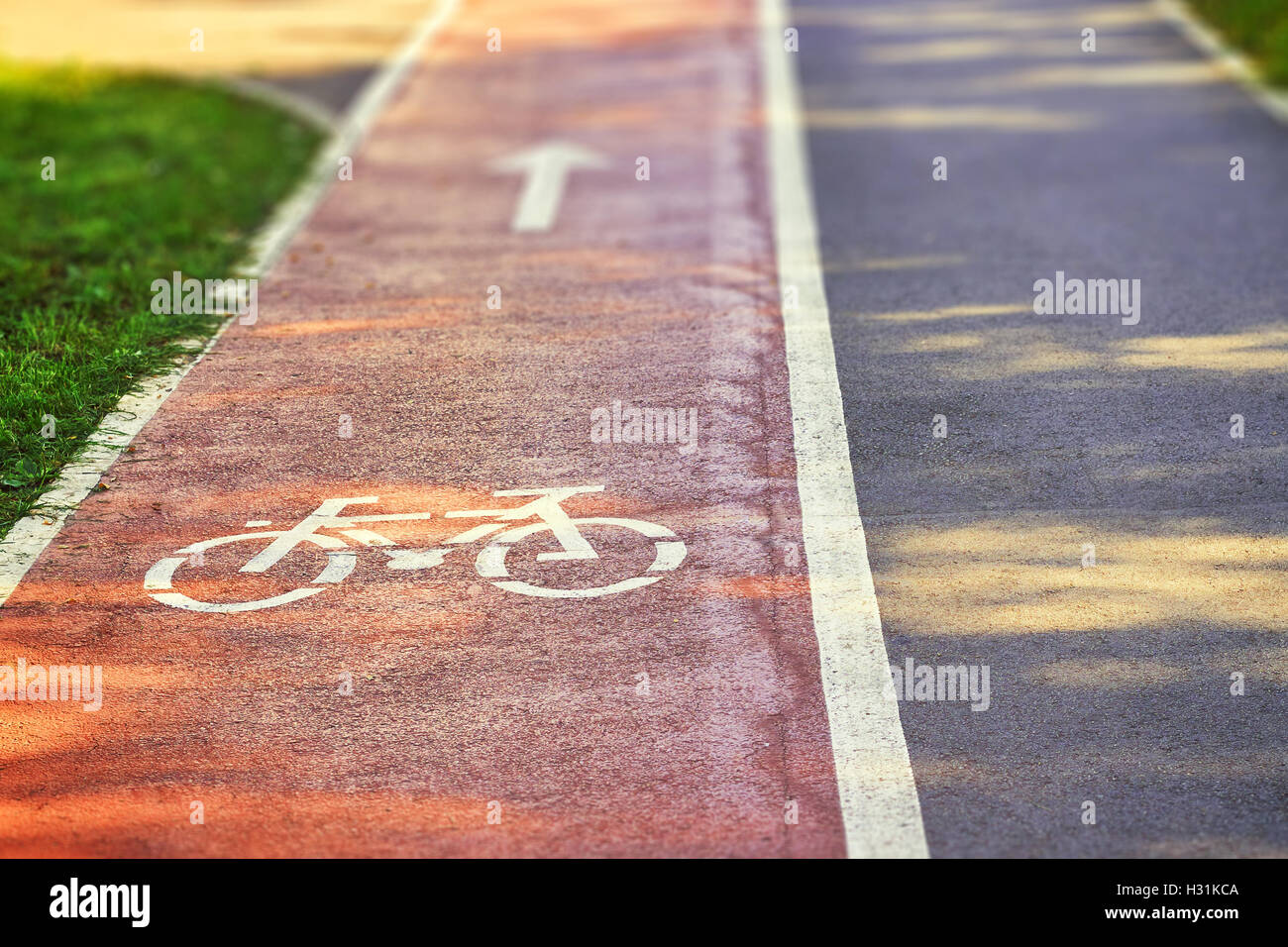 Red bike lane on sidewalk with painted white bicycle and arrow signs