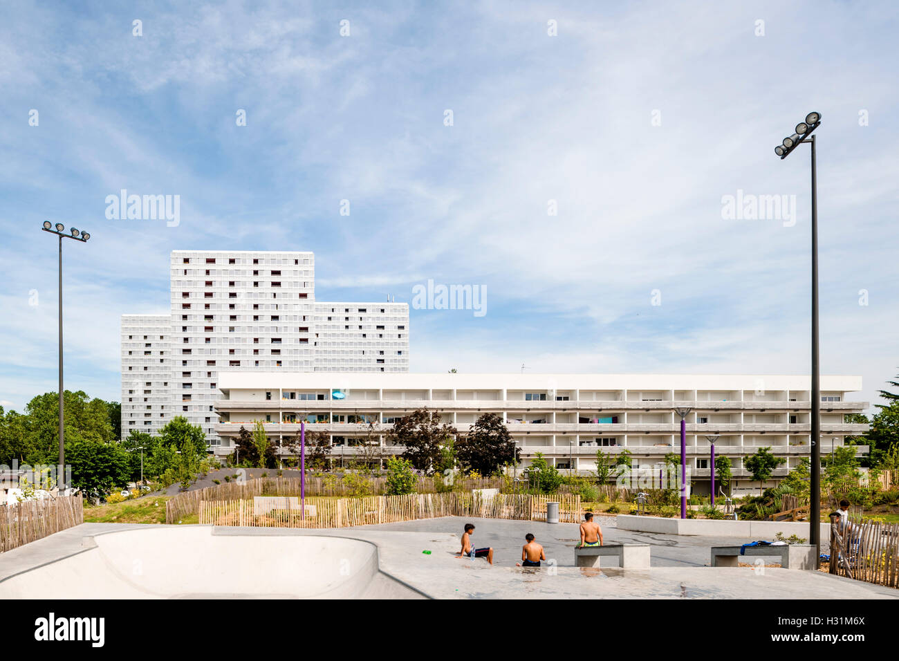 Long distance view from nearby skateboard park showing housing context. Urban Renovation Genicart Lormont in Bordeaux, Bordeaux, France. Architect: LAN Architecture, 2015. Stock Photo