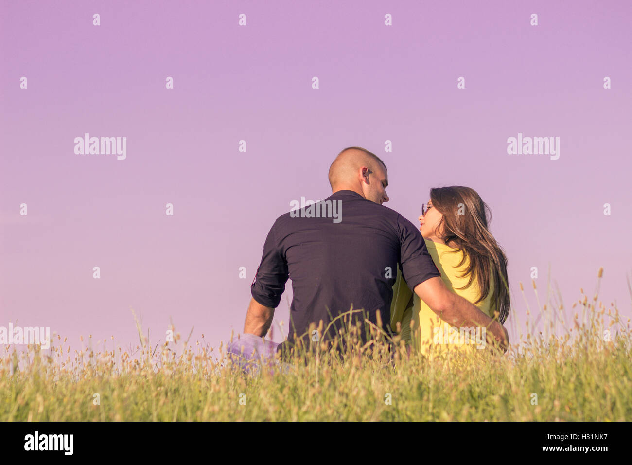young couple hugging back rear view low angle sky grass Stock Photo